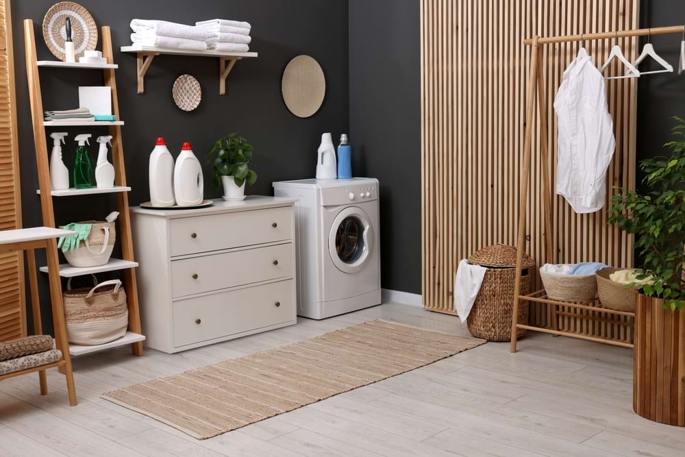 utility room with washing machine and rack for hanging clothes and chest of draws