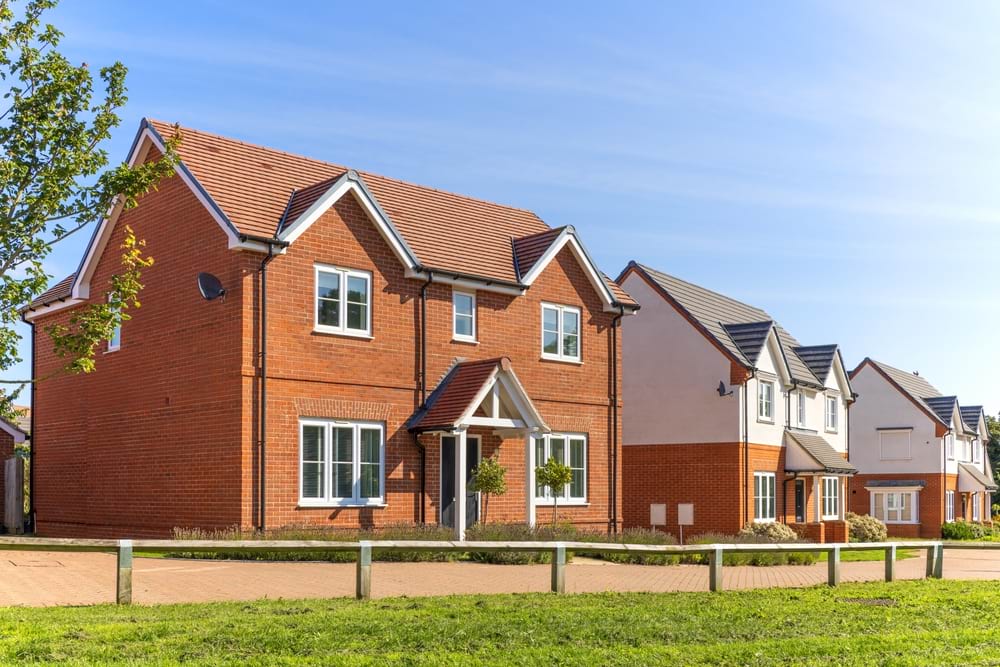 photo of three orange brick houses with some grass in front of them